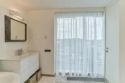 a white bathroom with a window and a sink at Vilnius city best view apartments in Vilnius
