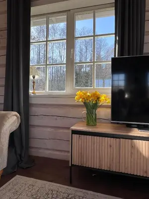 a living room with a television on a table with yellow flowers at Aviečių vila in Sumiliszki