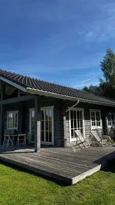 a small house with a wooden deck in front of it at Aviečių vila in Sumiliszki