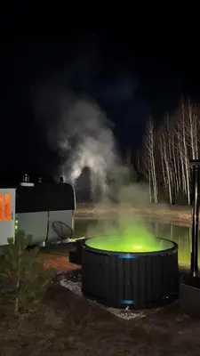a hot tub at night with smoke in the background at Aviečių vila in Sumiliszki