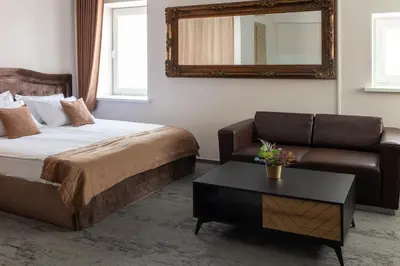 a bedroom with a bed and a couch and a mirror at Svečių Namai TEN in Marijampolė