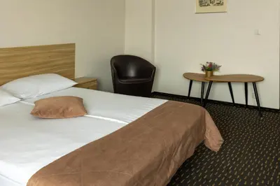 a hotel room with a bed and a chair at Svečių Namai TEN in Marijampolė