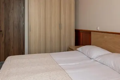 a bedroom with a white bed and wooden cabinets at Svečių Namai TEN in Marijampolė