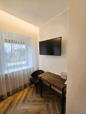 a room with a table and a television on the wall at Svečių namai 