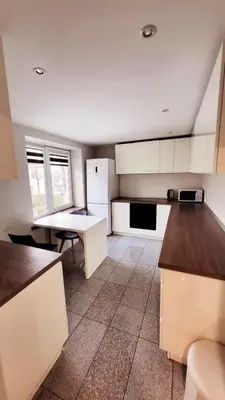 a kitchen with white cabinets and a white refrigerator at Svečių namai 