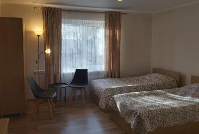 a hotel room with two beds and a table and chairs at Svečių namai 