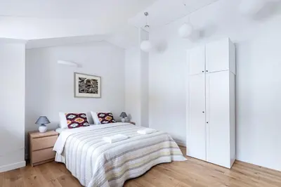 a white bedroom with a bed and a cabinet at Twin apartments 3 Bedr by Reside Baltic in Vilnius