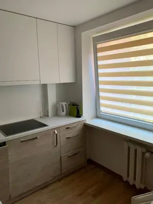 a kitchen with white cabinets and a window at Alytus Apartament in Alytus