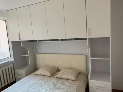 a bedroom with a bed with white cabinets at Alytus Apartament in Alytus