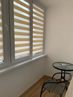 a table and a chair in a room with windows at Alytus Apartament in Alytus