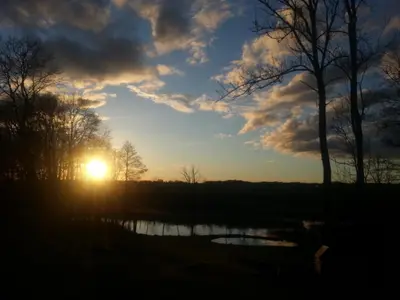 a sunset over a pond with the sun in the sky at Sodyba Širvynė in Užpaliai