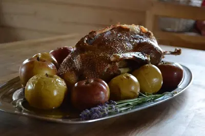 a roast chicken and apples on a plate on a table at Sodyba Širvynė in Užpaliai