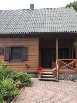 a house with a bench and flowers in front of it at Paukoje Apartamentai in Ignalina