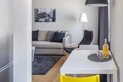 a living room with a white table and yellow chairs at Sun City Apartment in Šiauliai