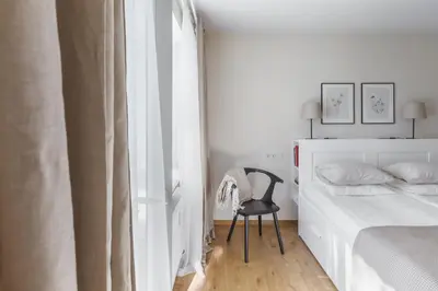 a bedroom with a bed and a chair next to a window at Sun City Apartment in Šiauliai