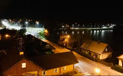a view of a city at night with a body of water at Cozy apartment with lake view in Trakai