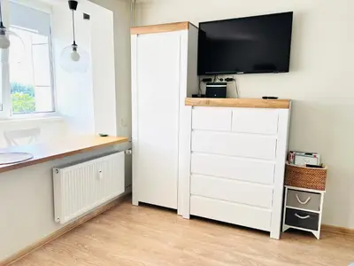 a room with a white cabinet with a tv on it at Cozy apartment with lake view in Trakai
