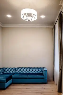 a blue couch in a living room with a chandelier at Kranto apartaments in Panevėžys