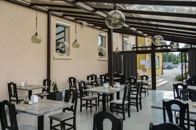a dining room with tables and chairs and windows at Armenia in Garliava