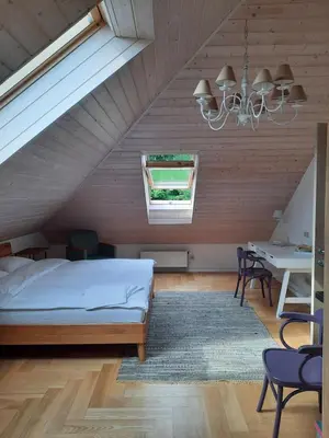 a bedroom with a bed and a table and a chandelier at Lake & Library boutique Hotel in Ignalina