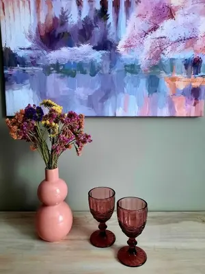 two vases with flowers in them on a table with a painting at Lake & Library boutique Hotel in Ignalina