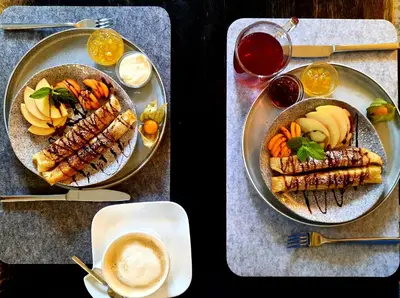 two plates of food with meat and vegetables and drinks at Lake & Library boutique Hotel in Ignalina