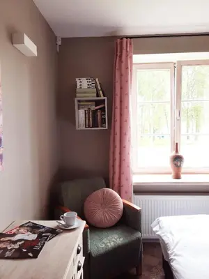 a bedroom with a chair and a table and a window at Lake & Library boutique Hotel in Ignalina