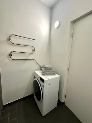 a laundry room with a washing machine and a towel at Mini Home Bookshop Studios in Vilnius