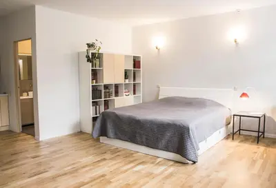 a white bedroom with a bed and a book shelf at Mini Home Bookshop Studios in Vilnius