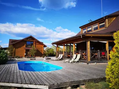 a house with a swimming pool on a wooden deck at Abromiškių Sodyba in Elektrėnai