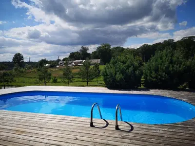 a large blue swimming pool on a wooden deck at Abromiškių Sodyba in Elektrėnai