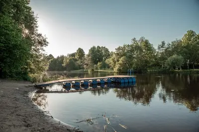 a dock on a river with trees in the background at Camping & Camper place Pasvalys in Pasvalys
