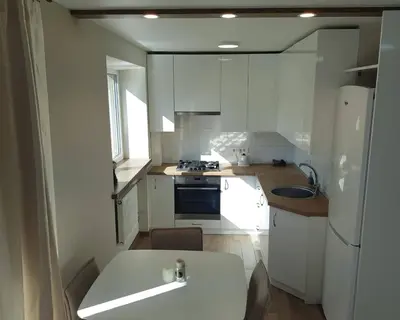 a small kitchen with white cabinets and a sink at Apartamentai Vilniaus Street II in Šiauliai