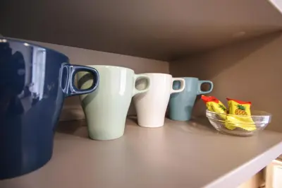 three coffee cups sitting on a counter with a bowl of chips at Svajonių apartamentai in Druskininkai
