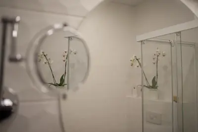 a mirror in a bathroom with flowers in at Svajonių apartamentai in Druskininkai