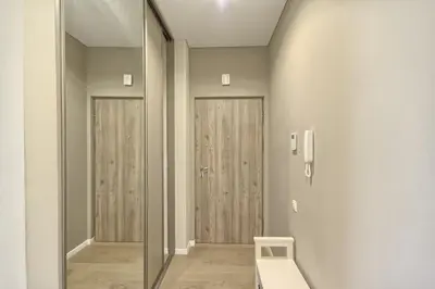 a hallway with two glass doors and a white chair at Svajonių apartamentai in Druskininkai