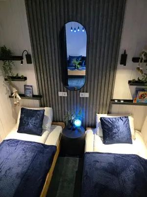 a room with two beds and a mirror and a tv at Economy rooms for 2-4 people in Anykščiai