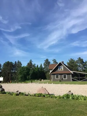 a house sitting on a beach in front of a yard at Economy rooms for 2-4 people in Anykščiai