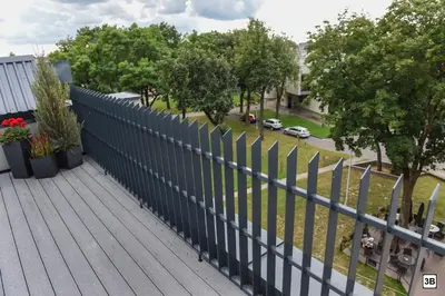 a fence on top of a deck with trees at Roof terrace apartment in Panevėžys