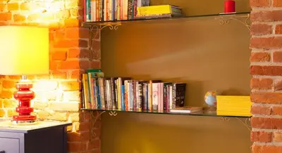 a book shelf filled with books next to a brick wall at Luxury Kaunas Old Town Apartment in Kaunas