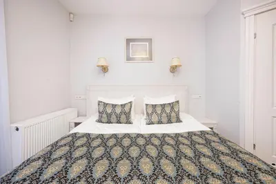 a white bedroom with a large bed with two pillows at Art Hotel in Druskininkai