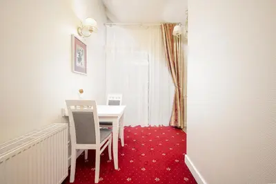 a dining room with a white table and red carpet at Art Hotel in Druskininkai