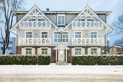a large white house with snow on the ground at Art Hotel in Druskininkai