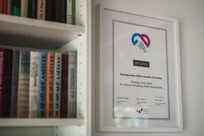a picture of a book shelf with a framed sign at SAKÀ Vacation House in Druskininkai