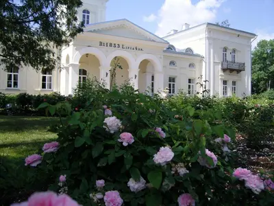 a white building with pink flowers in front of it at Burbiskio dvaras in Anykščiai