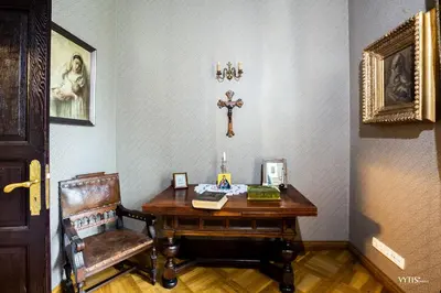 a room with a wooden table and a cross on the wall at Burbiskio dvaras in Anykščiai