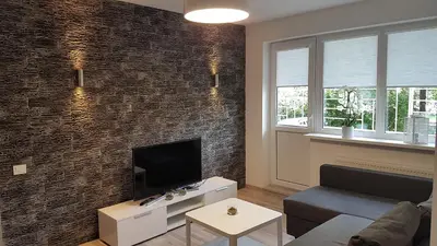 a living room with a tv and a brick wall at J&E NERIES Apartment in Kaunas
