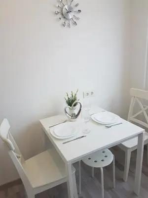 a white dining room table with two white plates and a vase at J&E NERIES Apartment in Kaunas