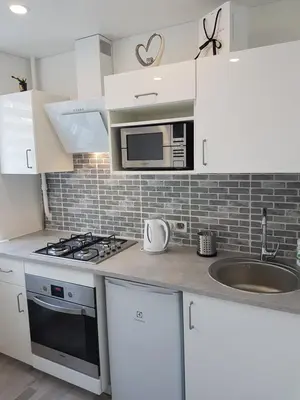 a kitchen with white cabinets and a stove and microwave at J&E NERIES Apartment in Kaunas