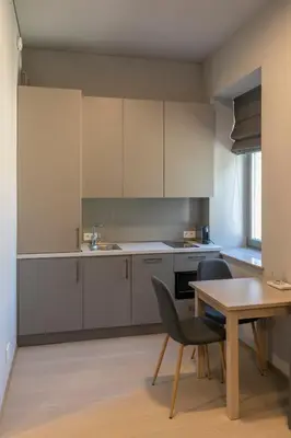 a kitchen with white cabinets and a table and chairs at APARTAMENTAI LEMBERGAS in Vilnius
